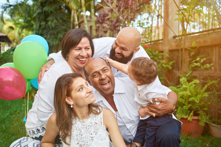 Familia junta en un jardin sonriendo con globos de colores