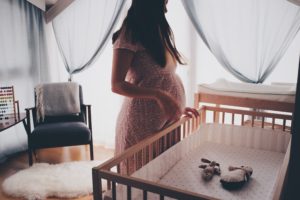 Mamá embarazada viendo una cuna con peluches