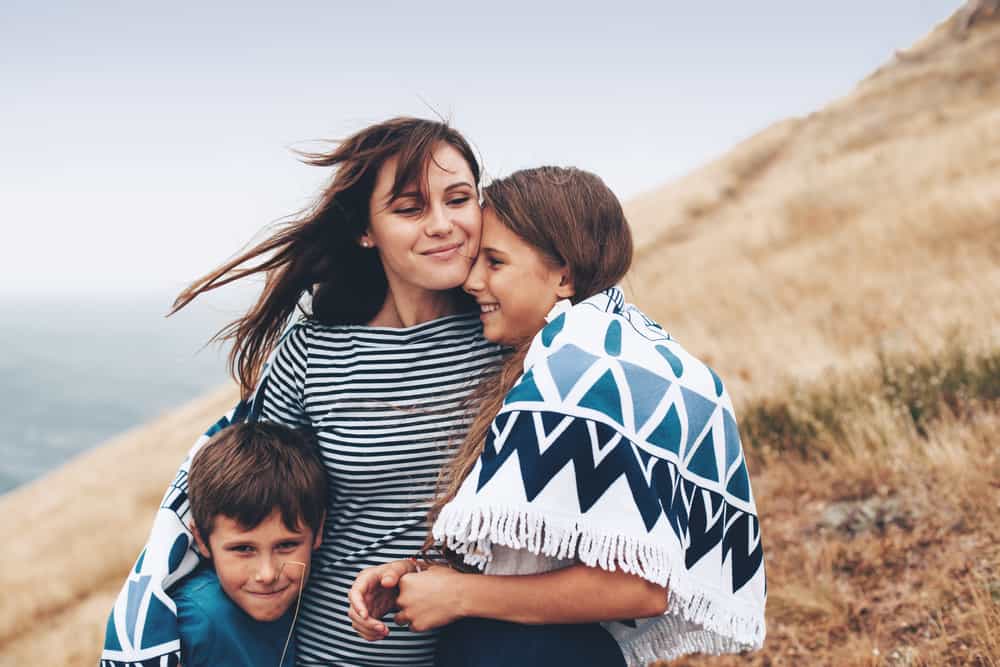 Mujer abrazando a sus hijos en una colina