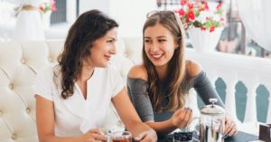 Madre e hija tomando té en un sofa