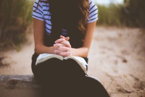 Manos de una mujer encima de una biblia orando