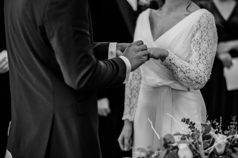 Fotografia de pareja de novios casandose y colocandose los anillos