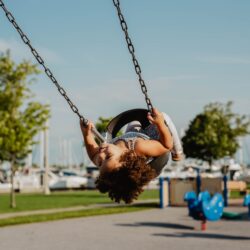 una niña pequeña usando una silla mesedora en el parque