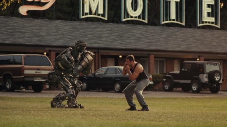 Hombre realizando una practica de boxeo junto a un robot de metal que realiza los mismo movimientos, Escena de la pelicula GIGANTES DE ACERO