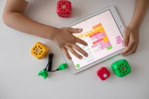 Un niño usando ua tablet y cubos de colores alrededor