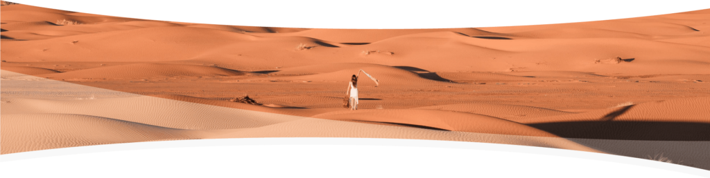 Mujer caminando por el desierto con levantando con su mano un pañuelo