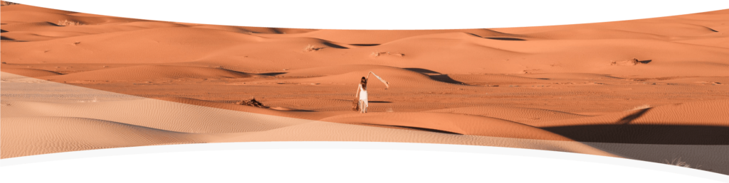 Mujer caminando por el desierto con levantando con su mano un pañuelo