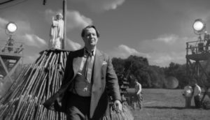 escena en blanco y negro de un hombre caminando en un set de filmación, Escena de pelicula MANK