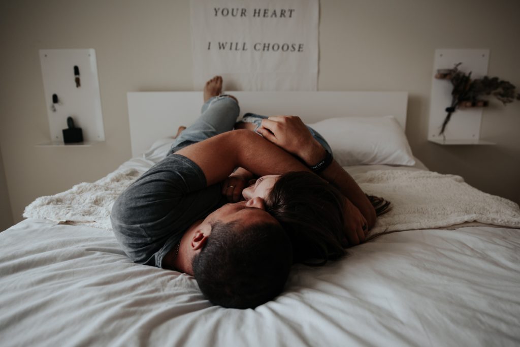Una pareja de esposos acostados abrazandose con un letrero en la pared que dice "Elijo tu corazón"