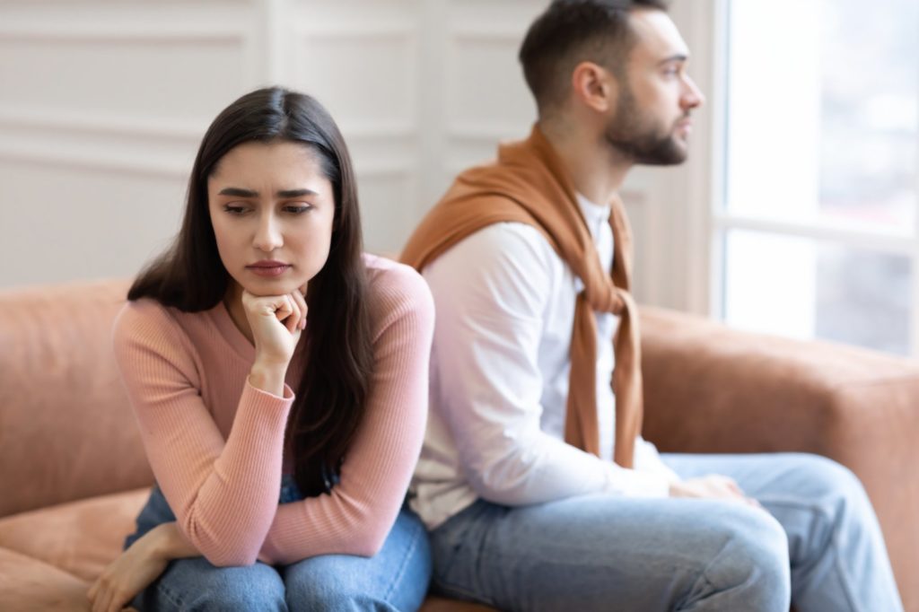 Pareja de Novios preocupados sentados en un sofa viendo a lugares contrarios