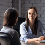 Mujer aconsejando a otra mujer sentadas a la mesa