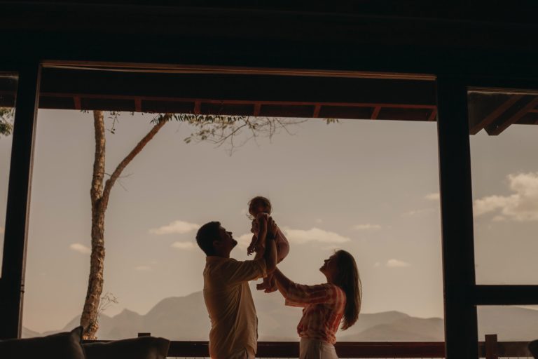 Padre y Madre alzando a su hija en una cabaña en la montaña