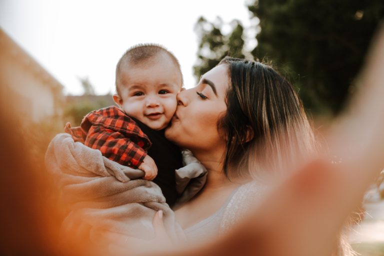 Mamá joven besando a su hijo pequeño