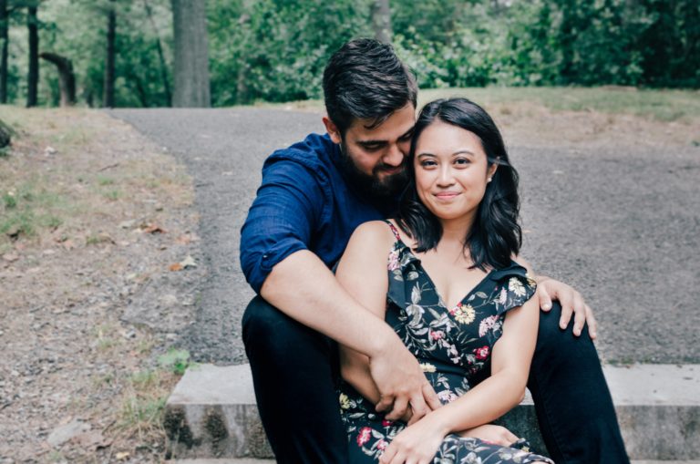 Una pareja de novios en un bosque sentados viendo a la camara alegres