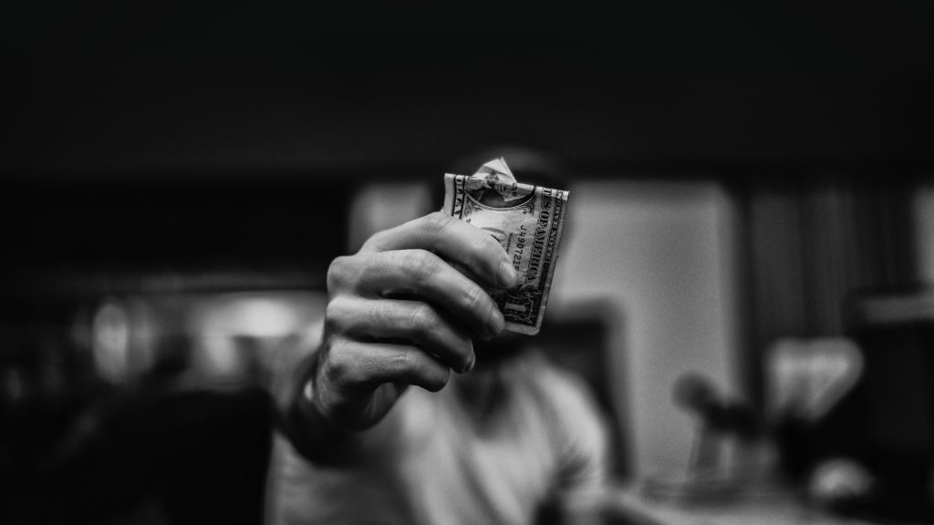 Imagen blanco y negro de un hombre sosteniendo un billete con una mano
