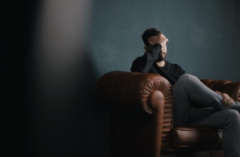 Hombre frustrado en el sillon sosteniendo su cabeza