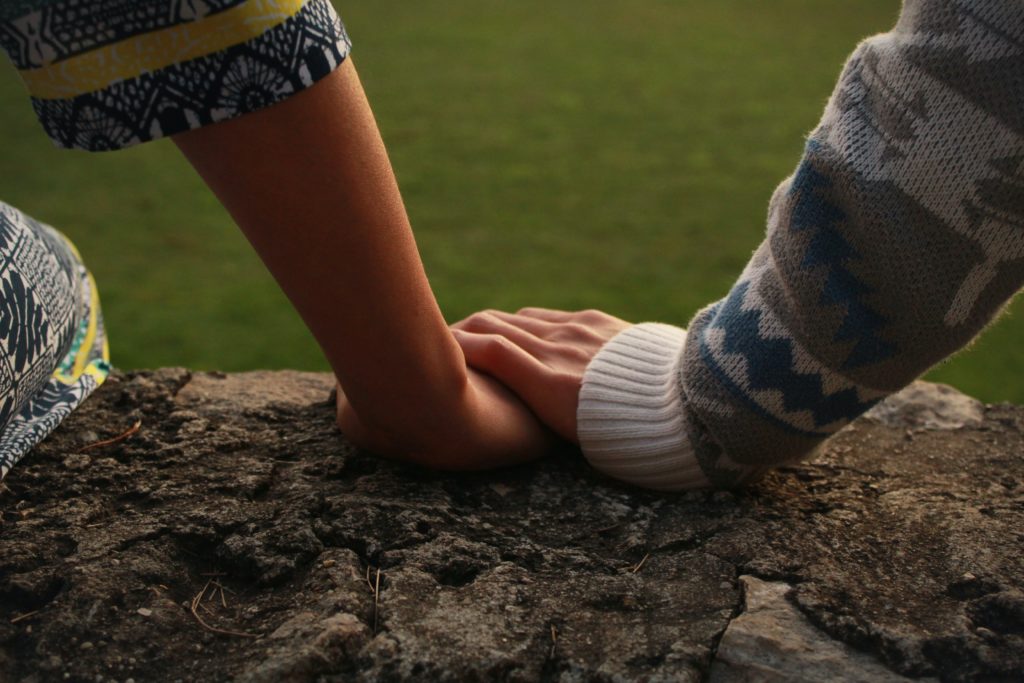 una mano sosteniendo una mano de una mujer joven