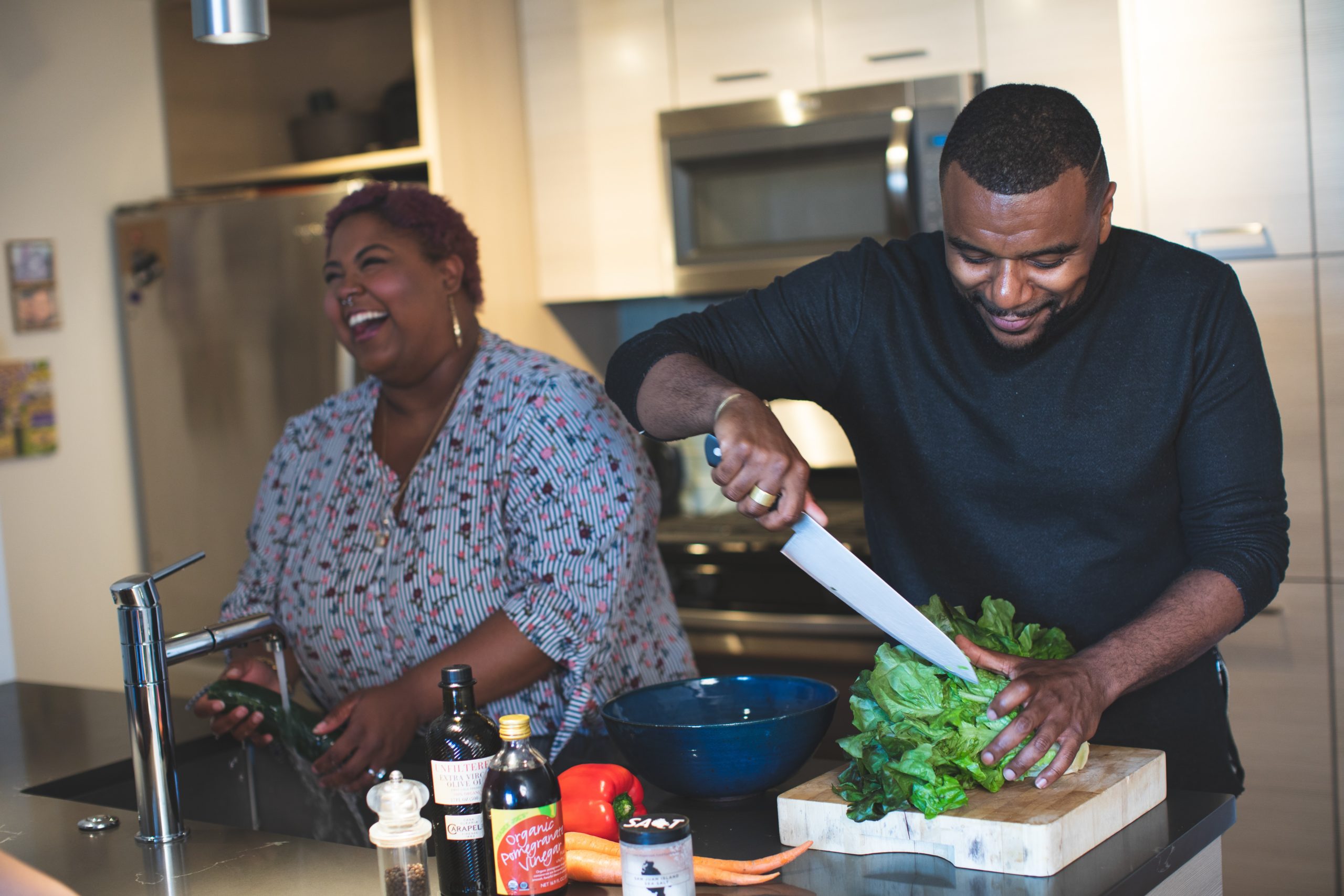 Pareja de Esposos cortando una lechuga en la cocina y lavando verduras