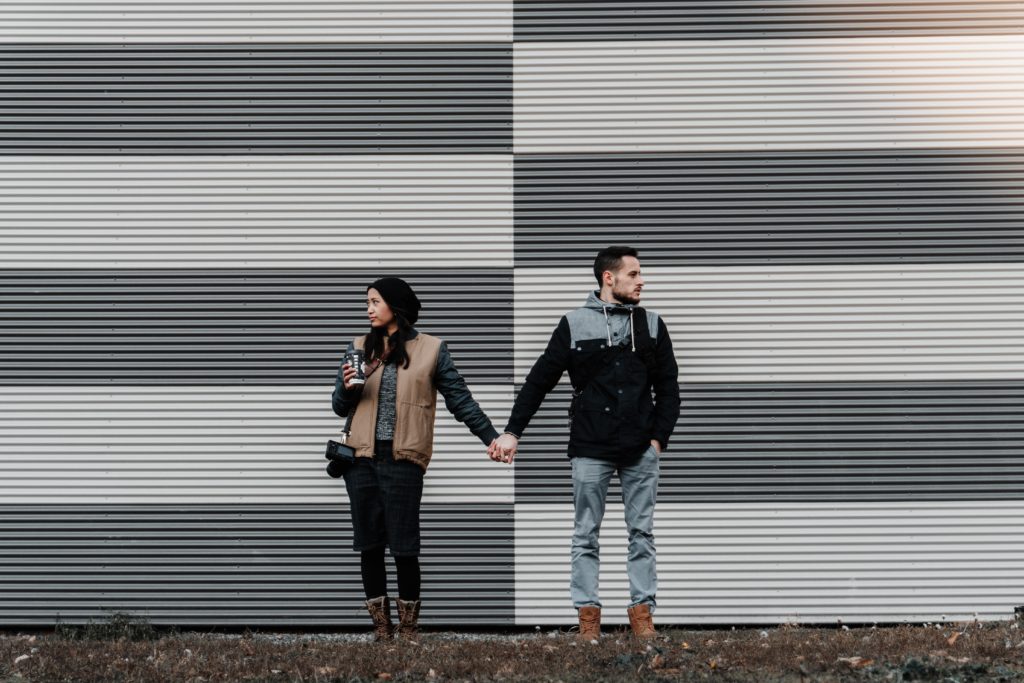 Pareja tomados de las manos viendo cada uno hacia un lado diferente