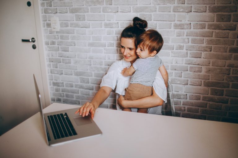 Mujer con su hijo en brazos frente a una computadora