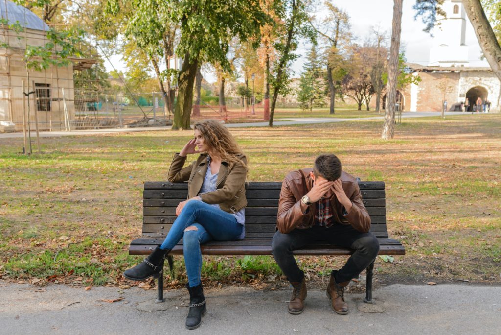 Mujer y hombre enojados en una banca en un parque