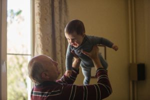 Abuelo tomando a su nieto en brazos y alzandolo mientras el niño rie