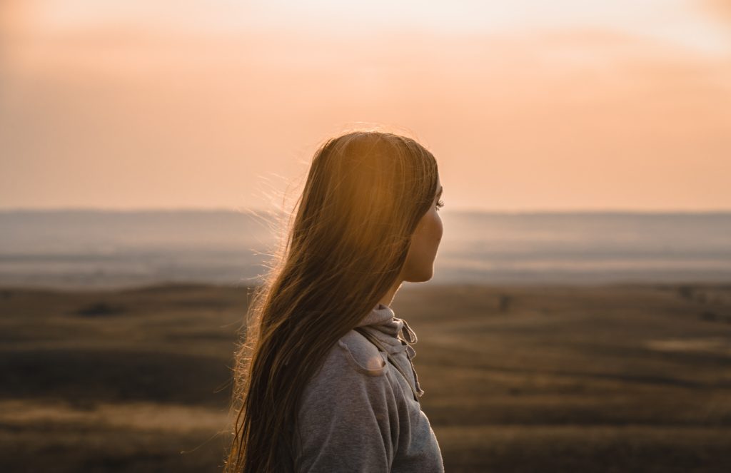 Mujer joven viendo el oceano desde la playa