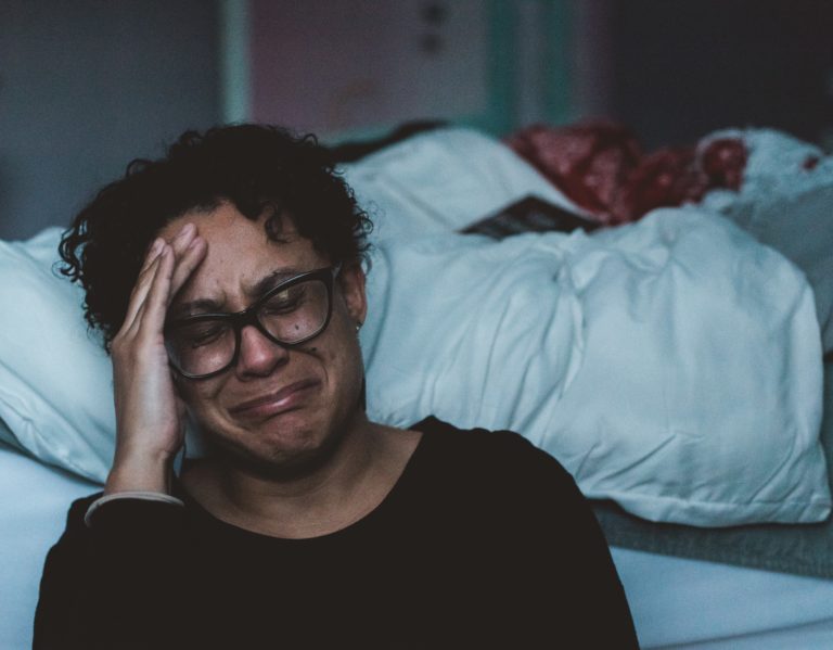 Mujer llorando a la orilla de la cama