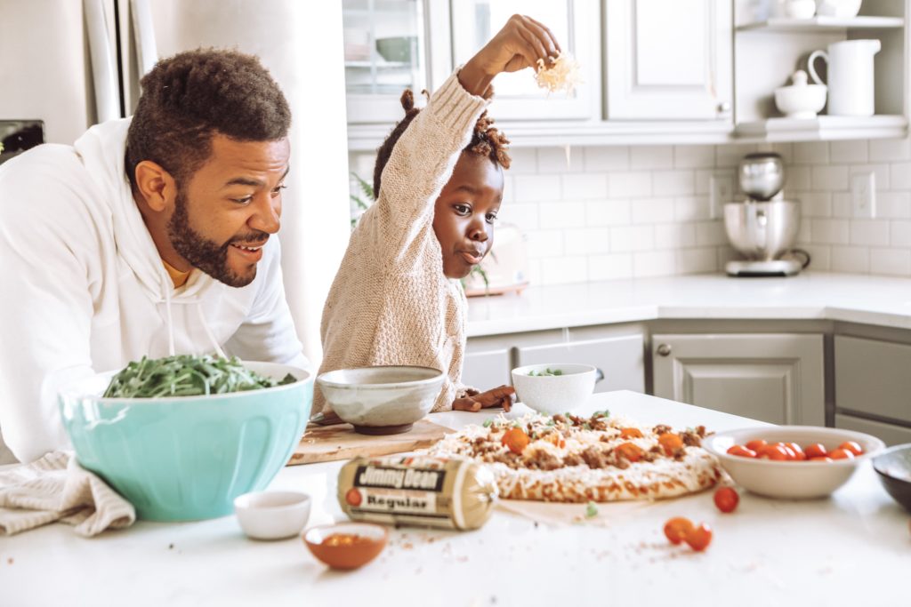 Hombre junto a su hijo preparando una pizza en la cocina