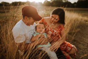 Esposo y su esposa con su hijo pequeño en un campo sonriendo