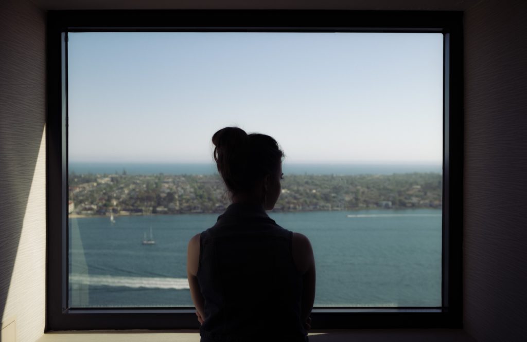 Mujer viendo un lago por una ventana