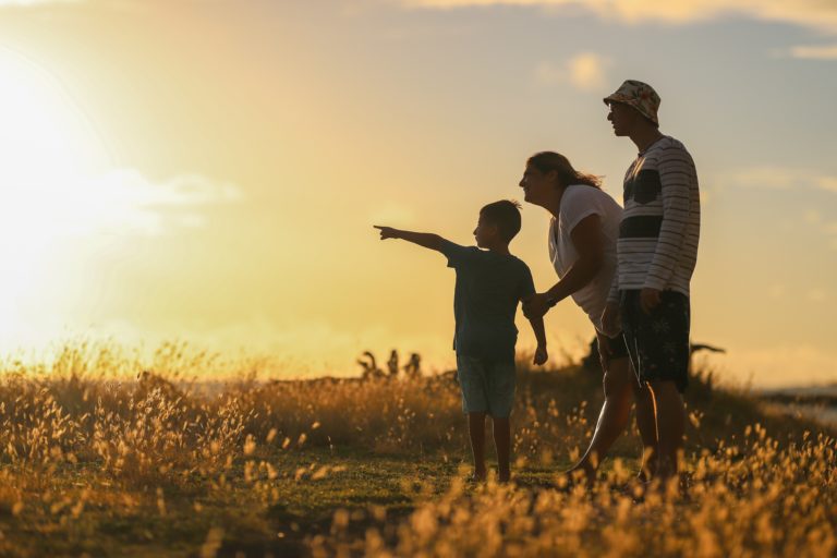 Niño señalando el atardecer junto a sus padres