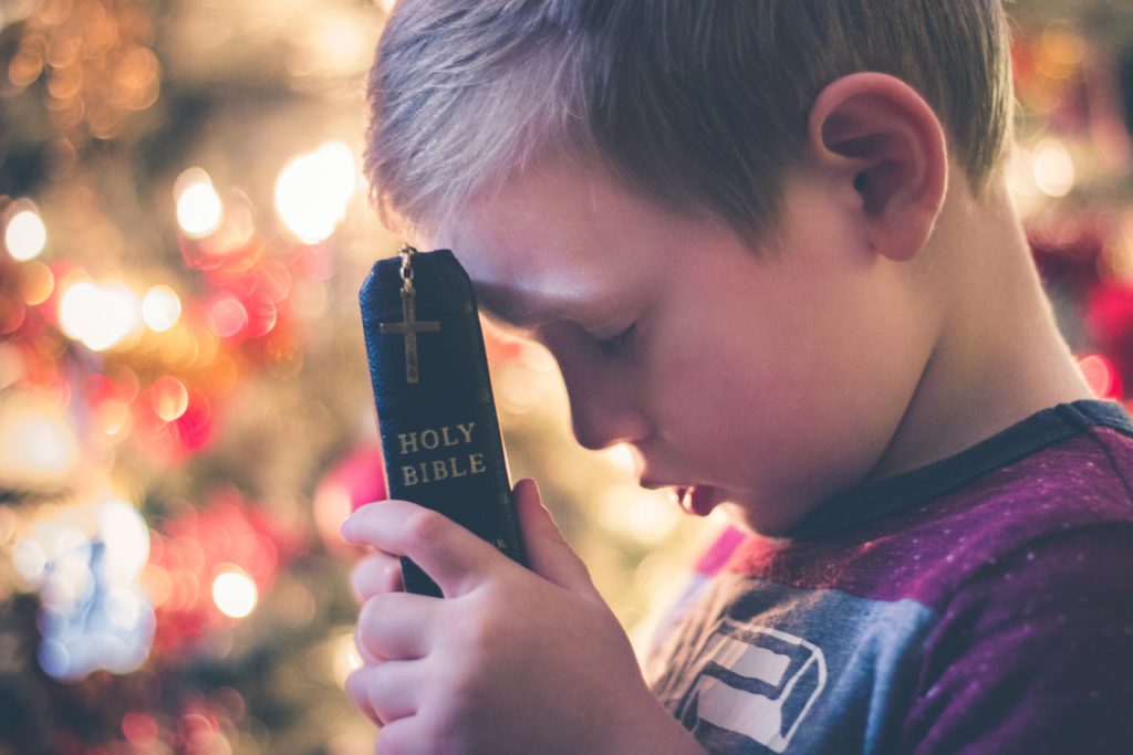Niño orando con la biblia
